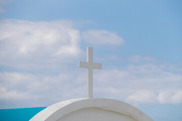 White classic cross, blue sky with white clouds in the background. Religion, faith and prayer concept
