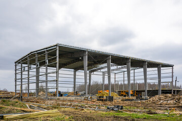 Construction site with metal frame of a unfinished industrial building and construction machinery