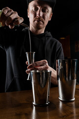 Bartender prepares Penicillin cocktail at the bar. Bartender mixes whiskey, lemon juice, and honey-ginger syrup to prepare the Penicillin alcoholic cocktail.