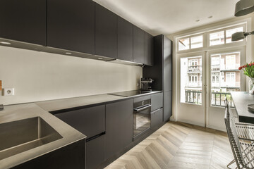 a modern kitchen with black cabinets and stainless steel appliances on the countertop, in front of an open window