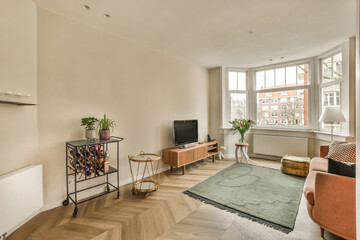 a living room with wood flooring and large windows looking out onto the street in front of the apartment building