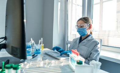 A scientist who focuses on a computer in a medical laboratory. The photograph shows a medical scientist entering data into a computer in a chemical laboratory.