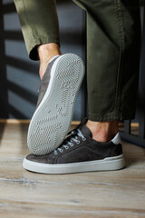 Close-up of male legs in pants and gray casual sneakers. Men's leather shoes. Collection of men's...