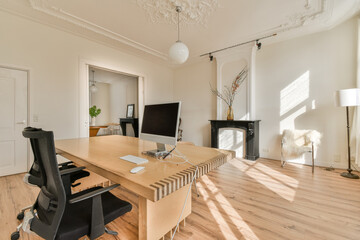 a nice home office with wood flooring and white walls, an open fire place in the room is visible on the right side