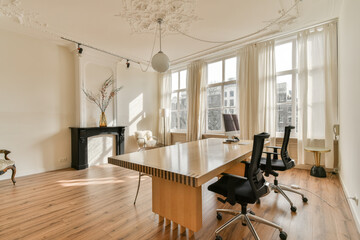 a living room with wood flooring and white curtains on the windows in the room is lit by bright sunlight