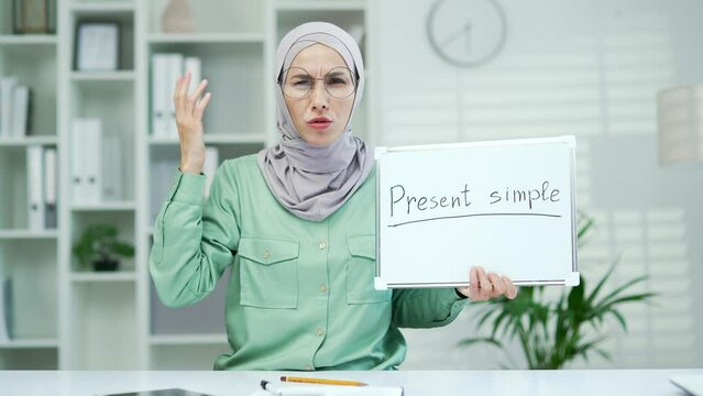 Evil angry Muslim woman quarrel teaching English lesson remotely, private tutor teacher talking on video call in classroom or home Study language webcam view learn course online look at camera