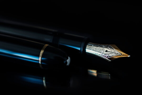 Montblanc Meisterst&uuml;ck 149 fountain pen. Pen with gold nib and embossed details on the side of the cap with the brand's symbol on a black surface with a black background.