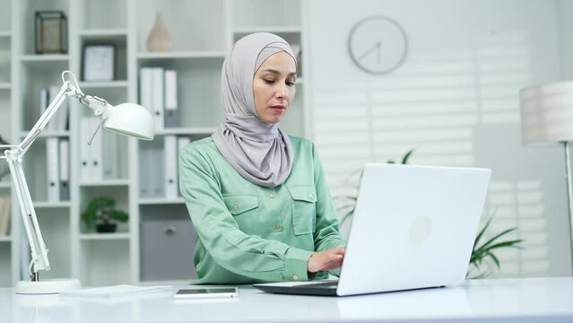 Thoughtful serious worker work on laptop computer in moderm office or home Confident muslim businesswoman freelancer think solving problem look for inspiration feeling lack of ideas at workplace