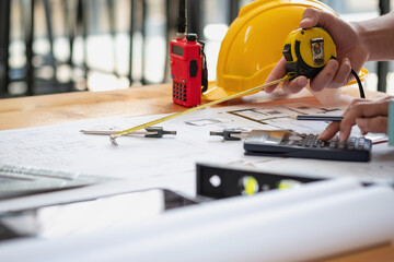 Asian engineers brainstorm and measure to document cost estimates and write floor plans for...