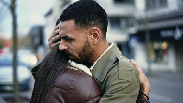 Young Arab man embracing woman standing in city street in empathy. Tracking shot of an affectionate compassionate couple. relationship support and gratefulness concept
