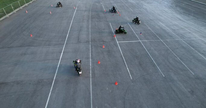 Motorcycle drivers improve their driving skills by driving between traffic cones, aerial view. Motorcycle school.