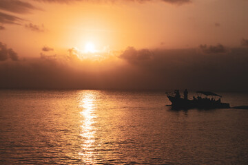 Obraz premium orange sunset in the sea with a tourism boat