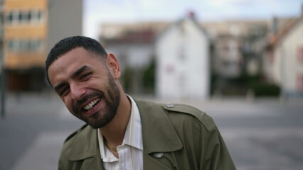 Obraz premium Portrait of a joyful Arab person smiling and laughing while standing in urban environment