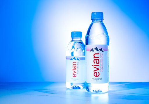Illustrative editorial of famous French Evian water bottles on blue background. Evian is a French brand of premium water: POLTAVA, UKRAINE - May 09, 2023.