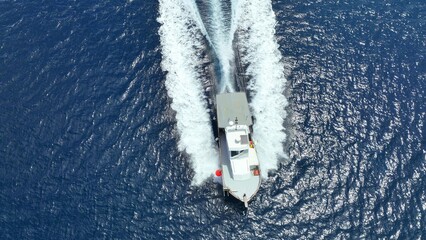 Aerial drone photo of boat cruising in high speed in deep blue sea, island of Mykonos, Cyclades,...