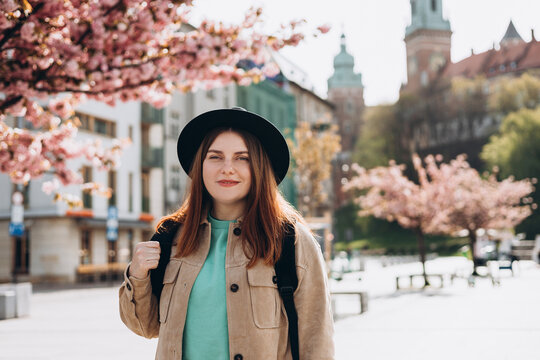 Young beautiful smiling hipster woman in trendy clothes. Sexy carefree woman with backpack posing on the street background. Positive model tourist outdoors. Cheerful 30s girl in hat is exploring city