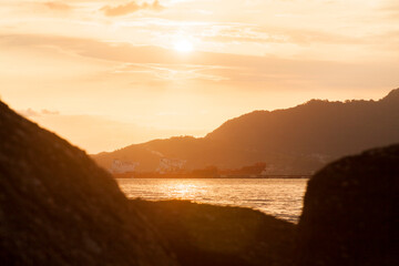 Golden sunset between rocks at Ilhabela beach. Paradisiacal and tropical Brazilian beach. Rocks concept. Golden sunset concept.