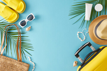 Summer holidays concept. Top view flat lay of suitcase flip flops sunglasses bag sunhat shell bracelet sunscreen and palm leaves on blue background with empty space for text or advert