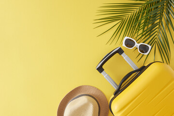 Summer getaway concept. Top view flat lay of stylish suitcase, sunhat, trendy sunglasses and palm leaves on light yellow background with empty space for text or advert