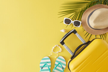 Summer travel concept. Top view flat lay of modern suitcase sunhat flip flops sunglasses shell bracelet and palm leaf on light yellow background with space for text or advert © Goncharuk film