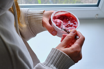 Young woman eating yogurt at home. Healthy snack