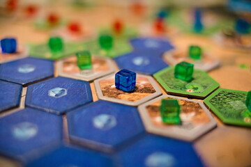 Żetony oraz elementy gry planszowej Terraformacja Marsa, widoczne niebieskie i brązowe płytki oraz niebieskie, zielone i czerwone kostki - obrazy, fototapety, plakaty