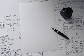 Blank sheet of paper and a pen on background with wireframes of IT project. User experience design...