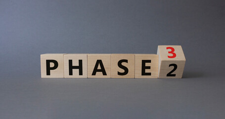 From Phase 2 to 3 symbol. Wooden cubes with words Phase 2 and Phase 3. Beautiful grey background....