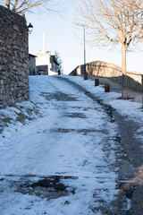 Obraz premium Snowy cobble stone paved road covered with ice and snow in a townscape winter scene in Bellver de Cerdanya