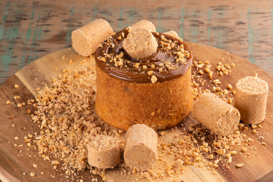 cake with dulce de leche cream with pa&ccedil;oca and peanuts on wooden board under rustic table close-up at an angle
