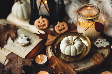Autumn home composition with aromatic candle, pumpkin, wool sweater, halloween homemade cookies. Aromatherapy on a grey fall morning, atmosphere of cosiness and relax. Holiday handmade decor - obrazy, fototapety, plakaty