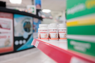 Cardiology pills bottle standing on pharmacy shelves ready for customers to come and buy drugs and vitamins. Drugstore carried a range of products, from prescription pills to home healthcare items.