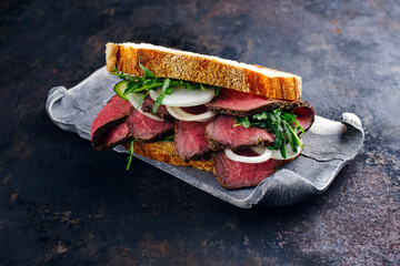 Traditional roast beef sandwich with rocket salad and onion rings served with an Italian ciabatta...