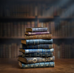 Stacks of old books on wooden desk in old library. Ancient books historical background. Retro style. Conceptual background on history, education, literature topics.