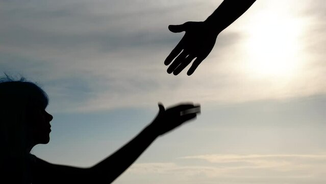 Silhouette of a hand reaching out to a teenager. The concept of helping a teenager.