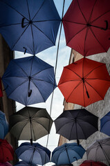 Colorful open umbrellas hanging against blue sky background. Bright street decoration