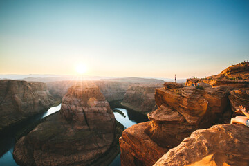 Man standing on the cliff of Horseshoe band and enjoing the sunset with the view of Colorado river in Arizona