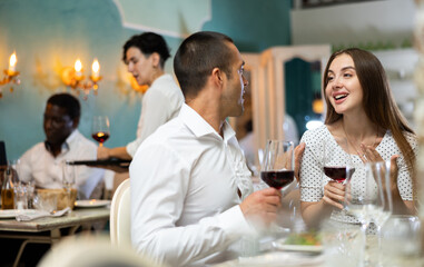 Positive couple drinking red wine in restaurant and talking