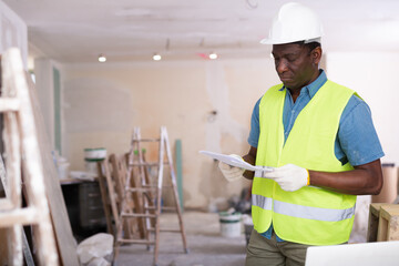 Portrait of confident foreman in a yellow vest with documents in his hands