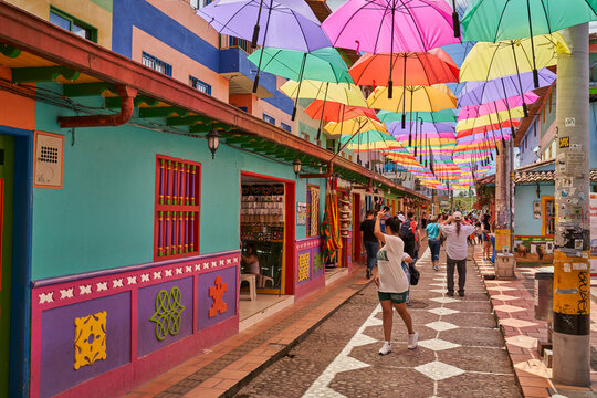 Old street in Guatap&eacute; Colombia with colorful umbrella's overhead with people taking pictures 