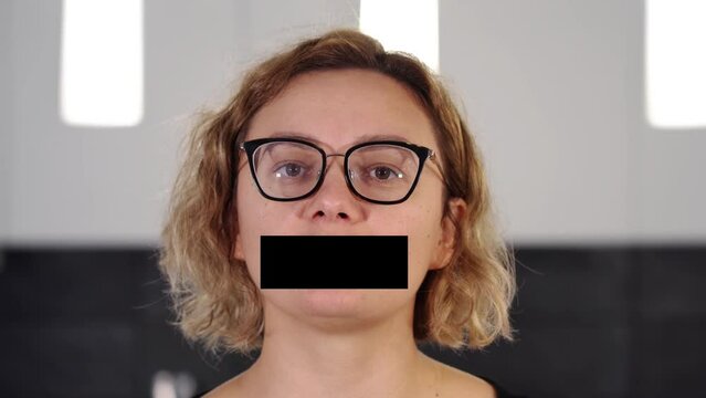 Serious young woman talks with virtual black strip on mouth