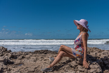 Mature woman relaxing outdoors sitting on the rocks near the sea.