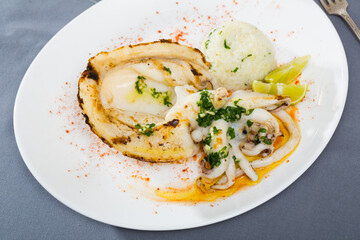 Grilled squid served with boiled rice, lime and garnished with chopped herbs