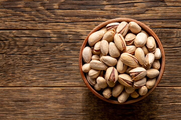 Bowl with pistachios on the old rustic wooden background. Dried nuts concept.