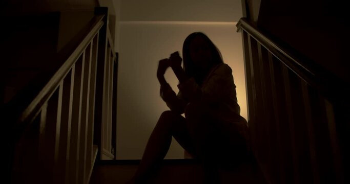 A lonely woman is sitting on the stairs at night . This concept use for symptoms of stress, major depressive disorder (MDD), psychotic symptoms.

