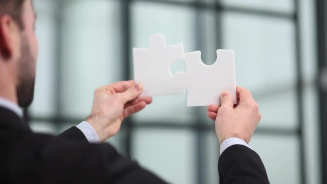 the business hands of a businessman are assembling puzzle pieces.