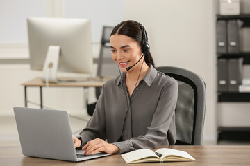 Hotline operator with headset working on laptop in office