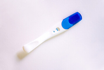 Positive pregnancy test with two stripes on white table.