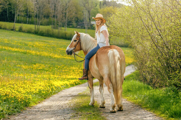 A young woman enjoying time with her haflinger horse in spring outdoors. Female equestrian...