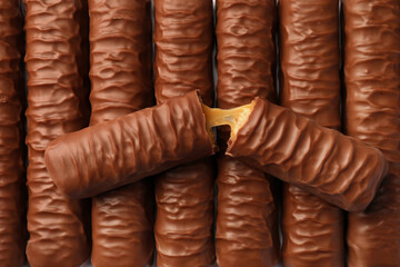 Sweet tasty chocolate bars with caramel as background, top view